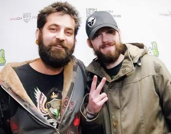 Dam Dunn from THSeeds and Tim Martin stand together at Hood Lab in Denver, 2012. They are in front of a backdrop with cannabis logos.