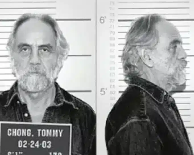 Mugshot of Tommy Chong from 2003, featuring front and profile views with a height chart in the background. He wears a denim shirt and maintains a stoic expression.