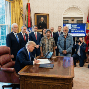 President signs an executive order related to marijuana policy while officials and media look on in the Oval Office.